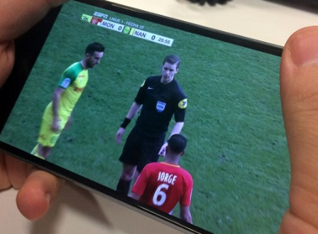 Човек који гледа фудбал на свом мобилном телефону преко дигиталних апликација